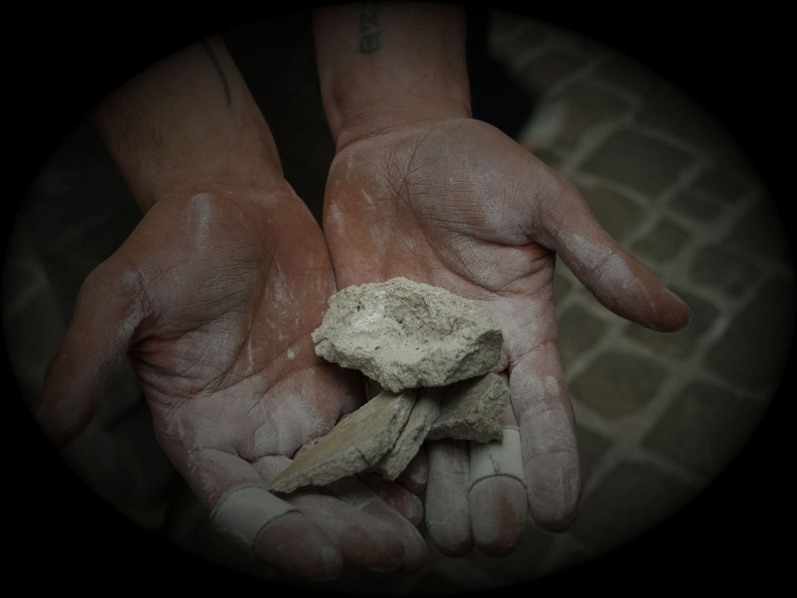 Due mani sporche di magnesite tengono schegge di roccia